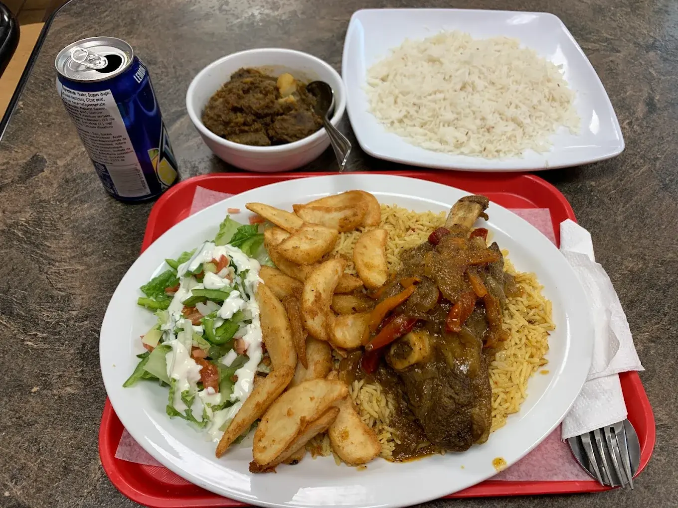 Halal lamb shank plate with seasoned rice, potato wedges and salad at Donair and Poutine House in Edmonton, AB