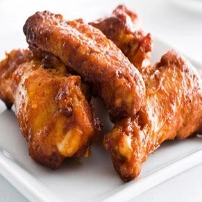 Saucy chicken wings plated with celery at Donair and Poutine House in Edmonton, AB